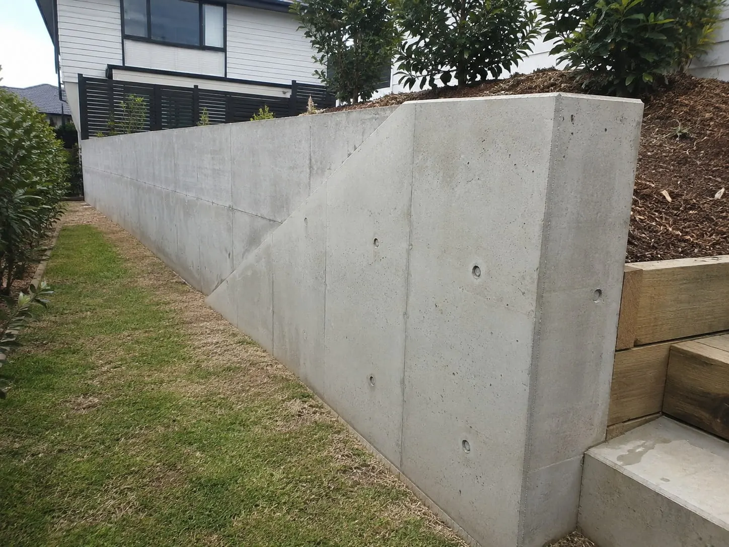 Poured concrete retaining wall stepping down beside an Auckland home